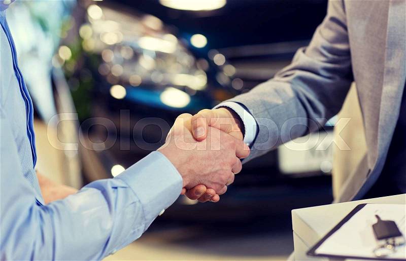 Auto business, car sale, deal, gesture and people concept - close up of male handshake in auto show or salon, stock photo