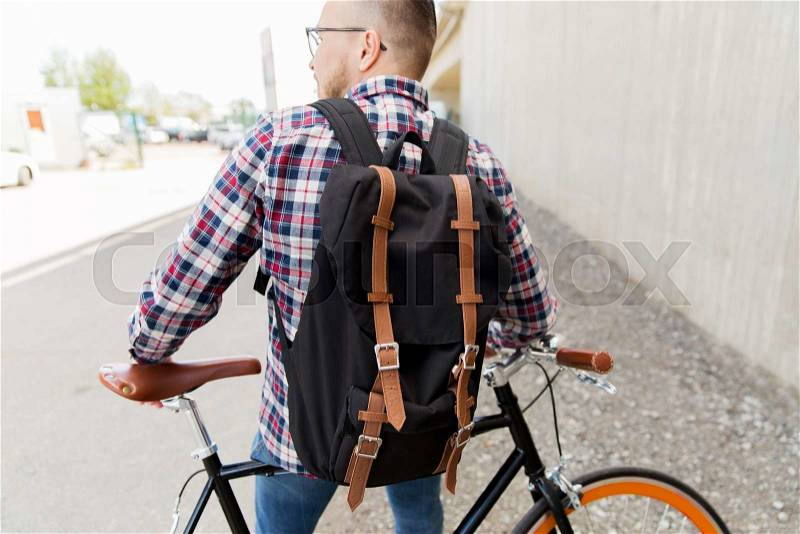 People, travel, tourism, leisure and lifestyle - young hipster man with fixed gear bike and backpack on city street, stock photo