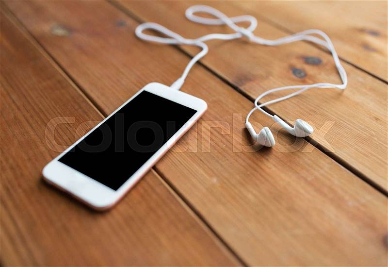 Technology, music, gadget and object concept - close up of white smartphone and earphones on wooden surface with copy space, stock photo