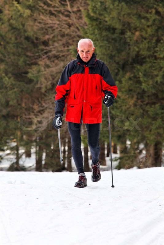 Senior at the snow in winter nordic walking, stock photo