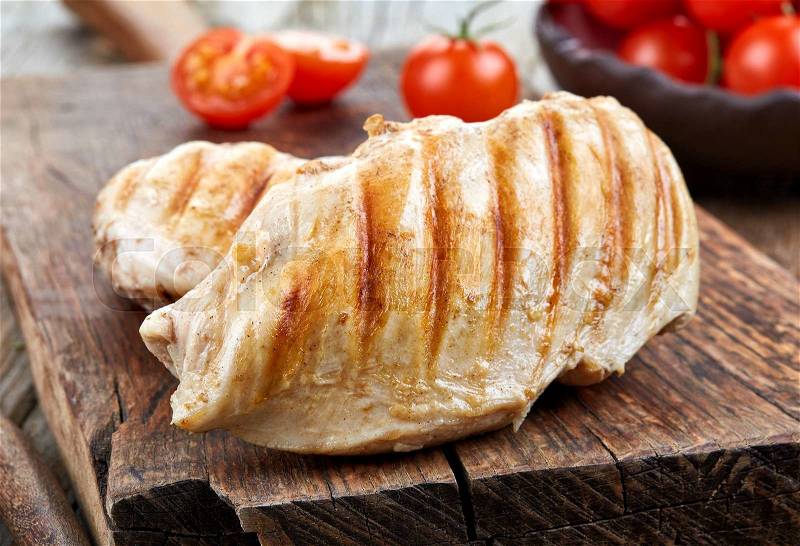 Grilled chicken breasts on wooden cutting board, stock photo