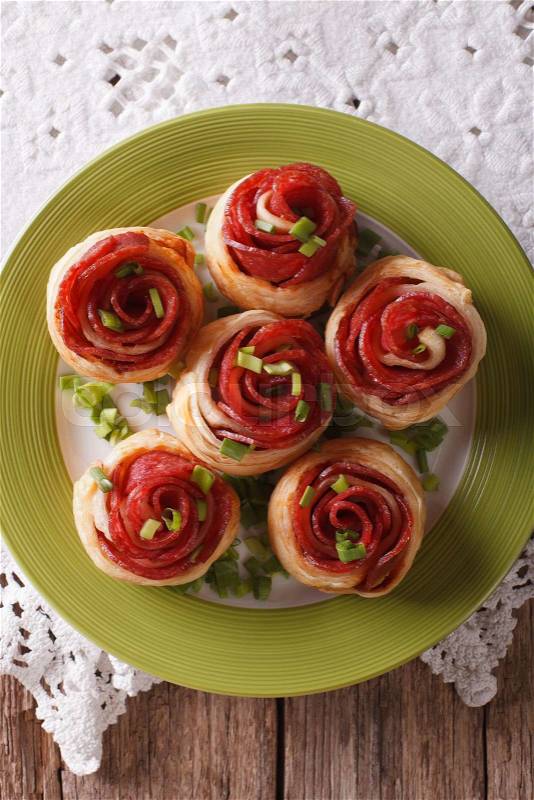 Baked rolls with salami in the form of roses on the table close-up. Vertical top view\, stock photo
