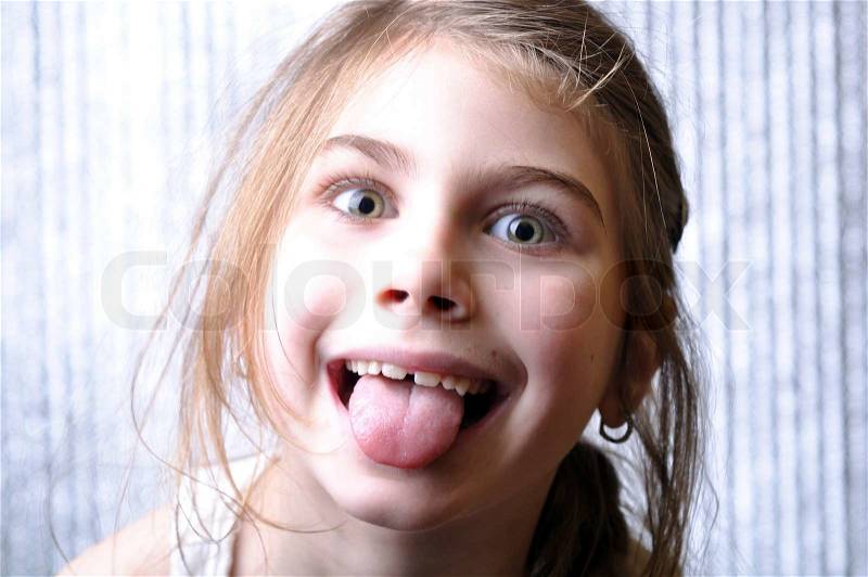 Close-up portrait of a cheerful girl with her tongue out, stock photo