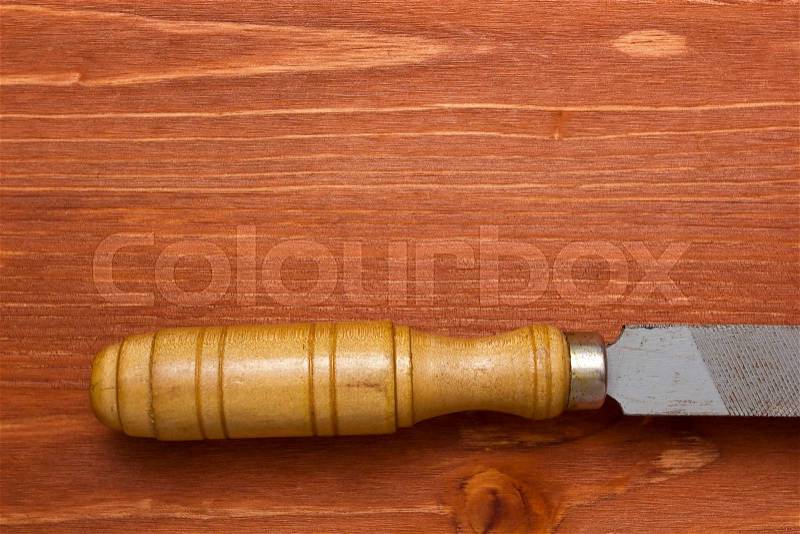 Old tool file rasp with wooden handle on a wooden background, stock photo