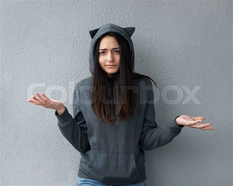Young girl at a loss against of textured wall, stock photo