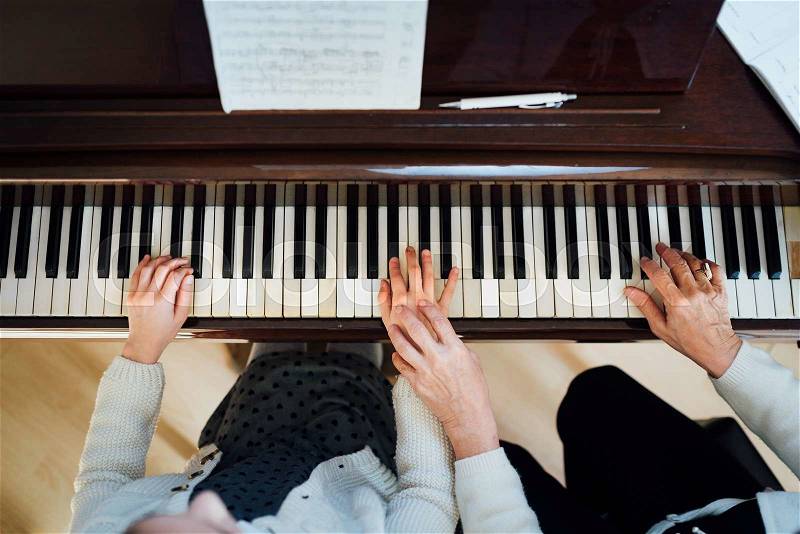 A music teacher with the pupil at the lesson piano, top view, stock photo