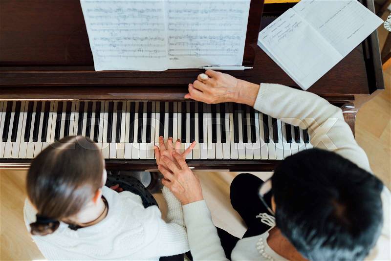 A music teacher with the pupil at the lesson piano, top view, stock photo