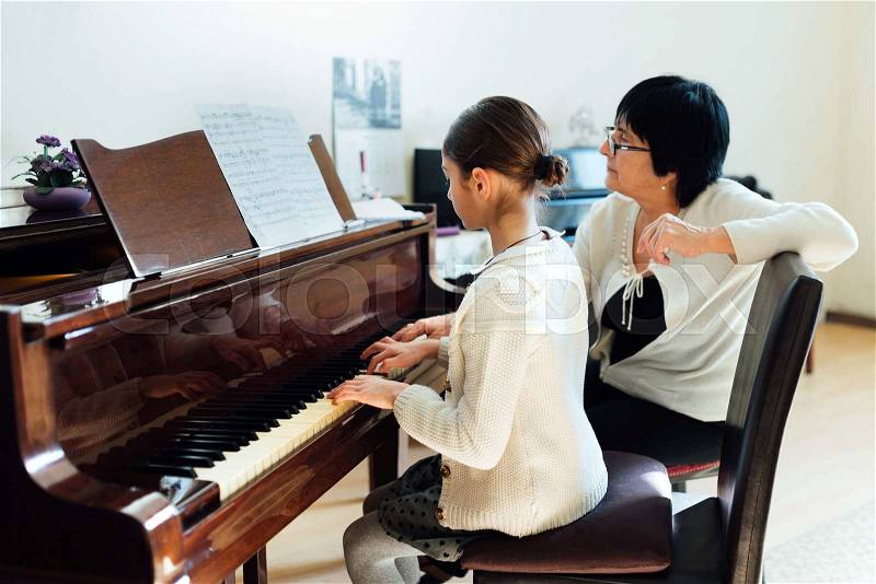 A music teacher with the pupil at the lesson piano, stock photo