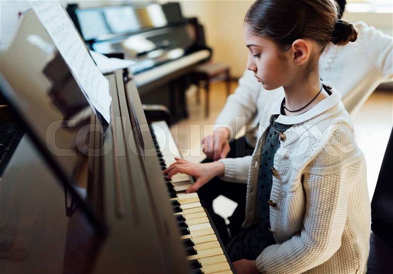 A music teacher with the pupil at the lesson piano, stock photo