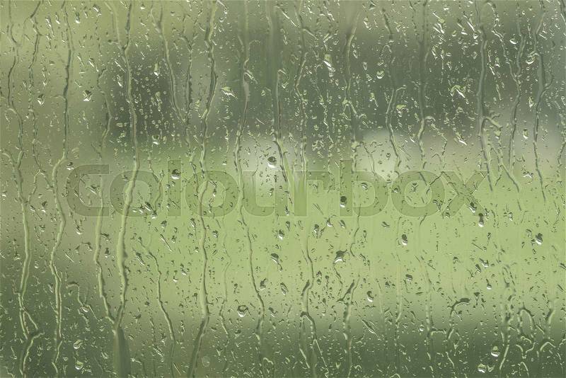 Window to a garden with rain drops in green color, stock photo