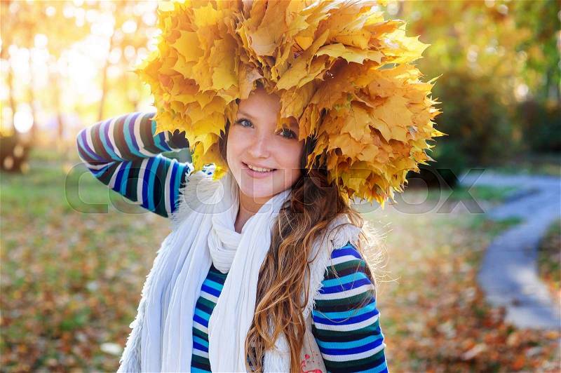Happy woman in a wreath of yellow leaves walking in autumn park, stock photo