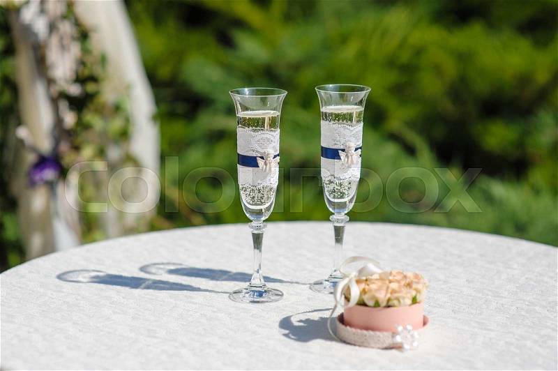 Two glasses with champagne and stand for rings on the table, stock photo