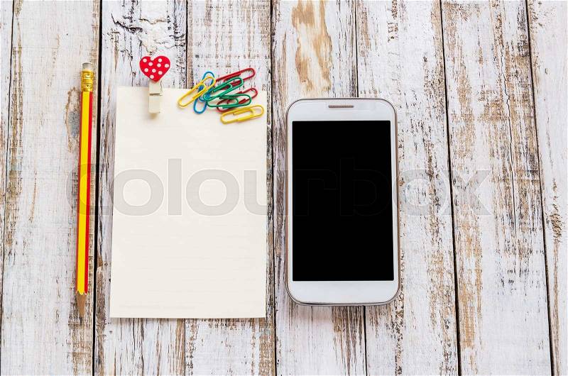 Paper,paperclip,pencil and smart phone on white wooden table background, stock photo
