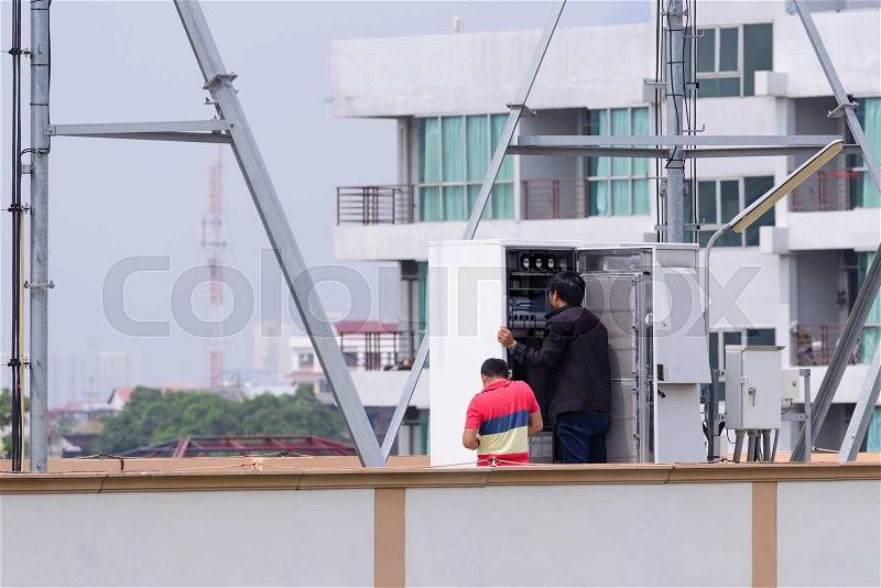 Technician support installing internet cable in controller box on the roof, stock photo
