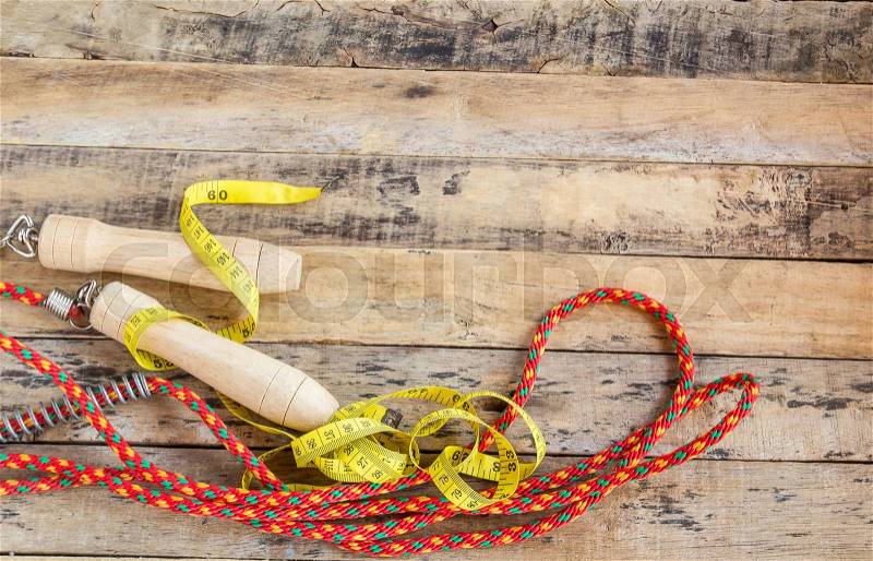 Skipping rope and measuring tape for an exercise on the wooden table, stock photo