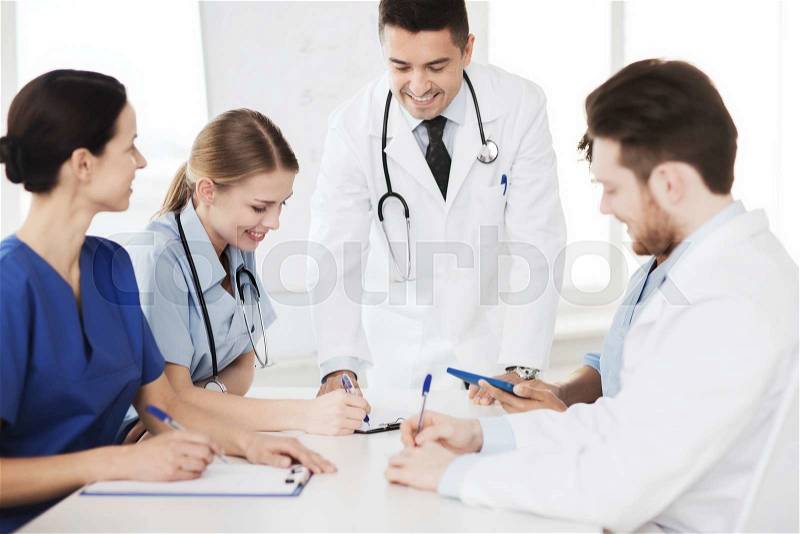 Hospital, profession, people and medicine concept - group of happy doctors meeting and taking notes at medical office, stock photo