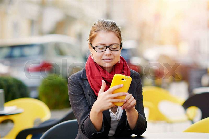 Young business woman is using smart phone for work in cafe, stock photo