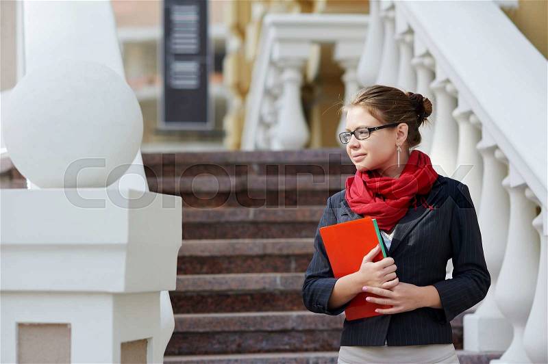 Closeup portrait of pretty young student girl holding exercise books and folder, stock photo