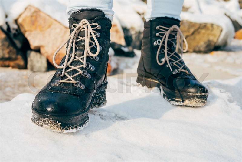 Female feet in high winter boots standing in the snow close-up, stock photo