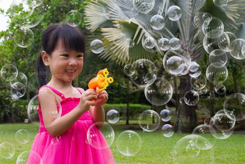Asian Little Chinese Girls Shooting Bubbles from Bubble Blower in the Park, stock photo