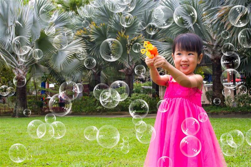 Asian Little Chinese Girls Shooting Bubbles from Bubble Blower in the Park, stock photo