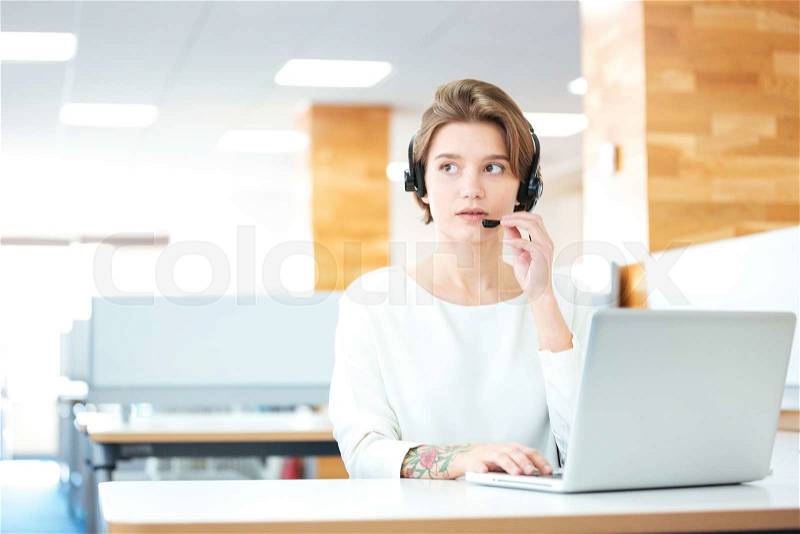 Beautiful young woman with headset working in call center, stock photo