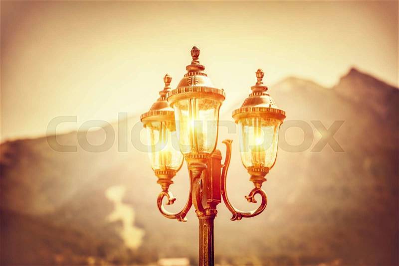 Beautiful vintage street lamp glowing in the evening over high mountains background, amazing antique architecture detail, Seefeld, Austria, Europe, stock photo