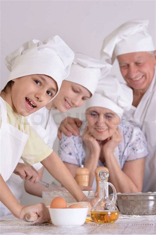 An elderly couple and their grandson knead the dough for the pie together, stock photo