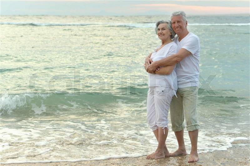 Nice old couple running on sea beach, stock photo
