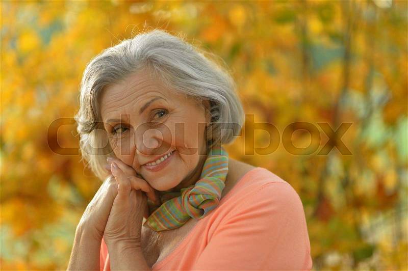 Happy beautiful senior woman in the autumn park, stock photo