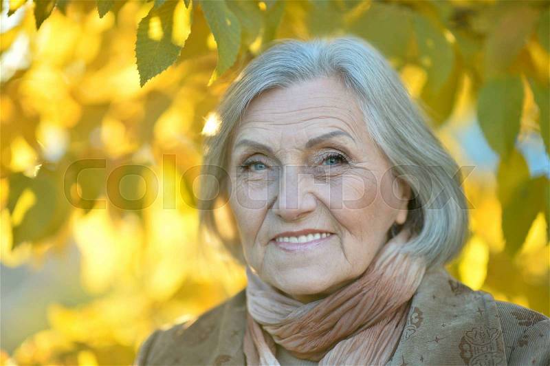 Happy beautiful senior woman in the autumn park, stock photo