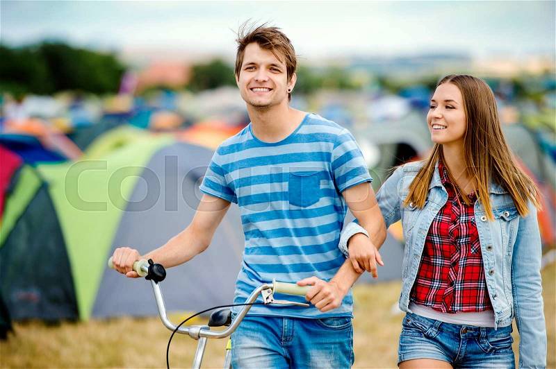 Teenage boy and girl in love with bike at summer music festival in a tent sector, stock photo