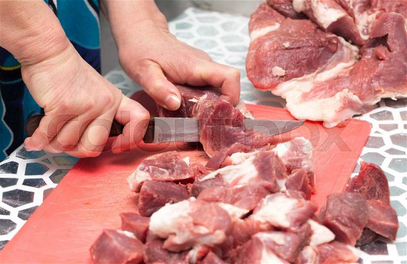 Cutting meat with a knife, stock photo