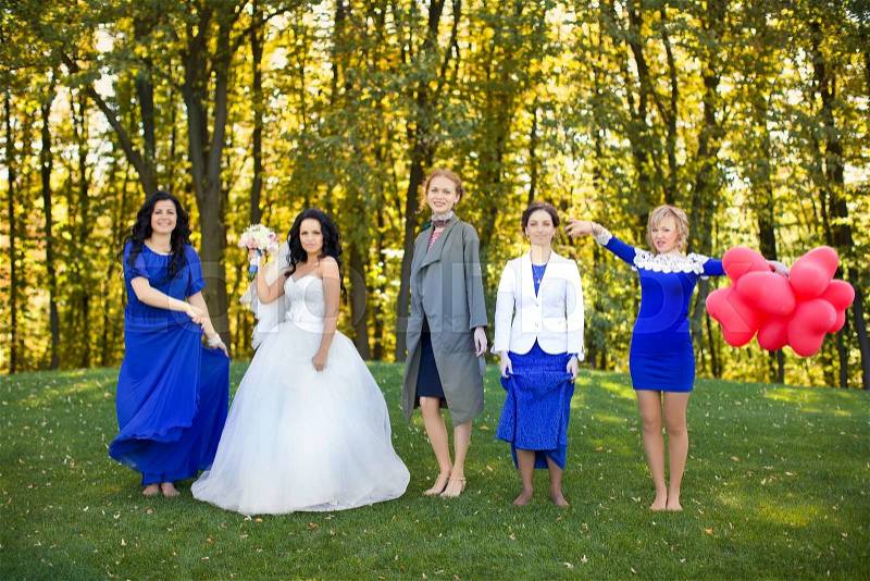 Outdoor portrait of beautiful young bride with her female friends, stock photo