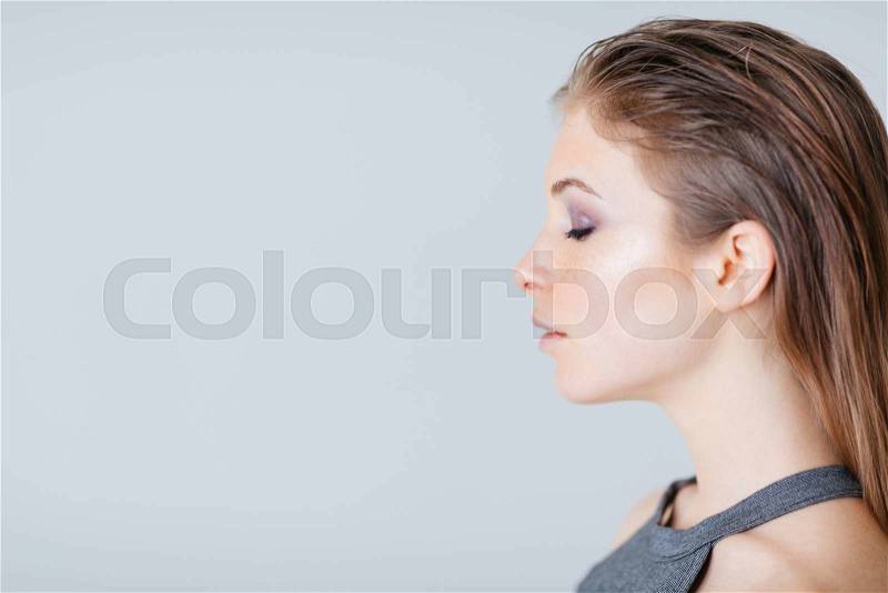 Side view portrait of a lovely woman over gray background, stock photo