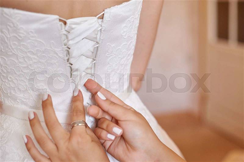 Bridesmaid helps bride to dress in the morning, stock photo