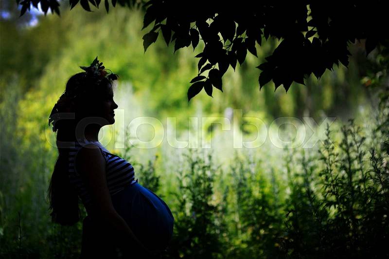 Silhouette of a happy pregnant woman in the garden, stock photo