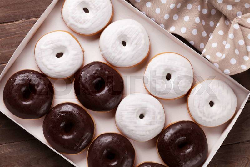 Donuts in box on wooden table. Top view, stock photo