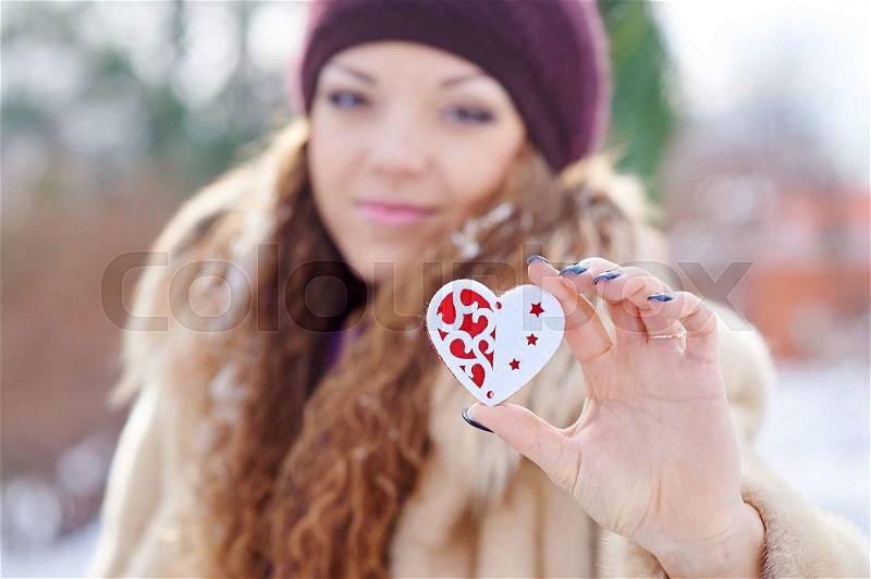 Woman holding a little heart in winter park, stock photo