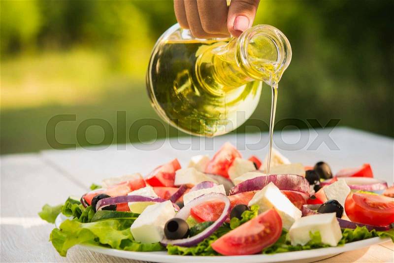 Fresh Caesar salad on white wooden table in the garden. Cooking outdoors, stock photo