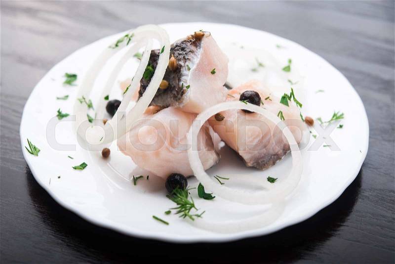 Fresh herring fish with spices on white plate, stock photo