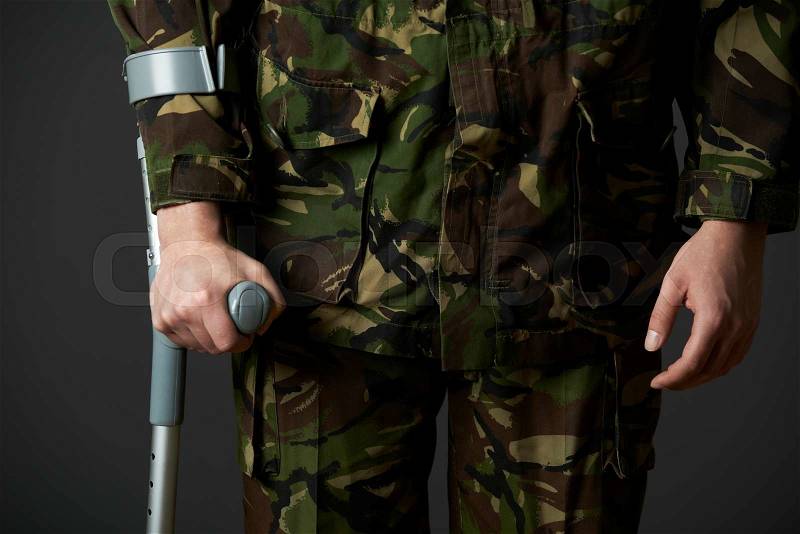 Studio Shot Of Wounded Soldier Using Crutch, stock photo