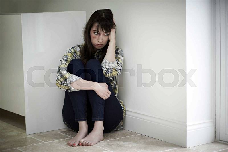 Female Victim Of Domestic Abuse Sitting On Floor, stock photo