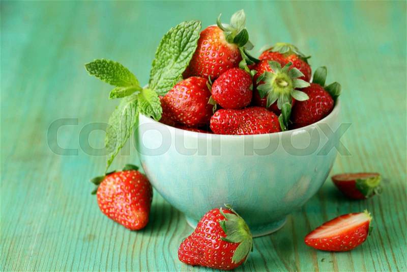 Fresh sweet ripe strawberries in a bowl on a wooden table, stock photo