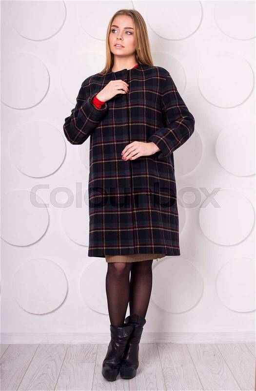 Young woman in the studio, measures the coat, stock photo