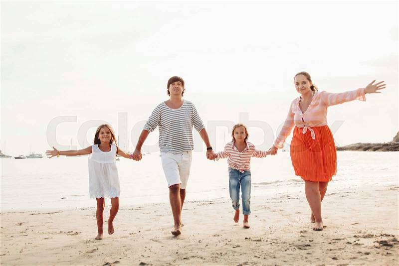 Family walking on the evening beach during sunset, travel photo series, stock photo