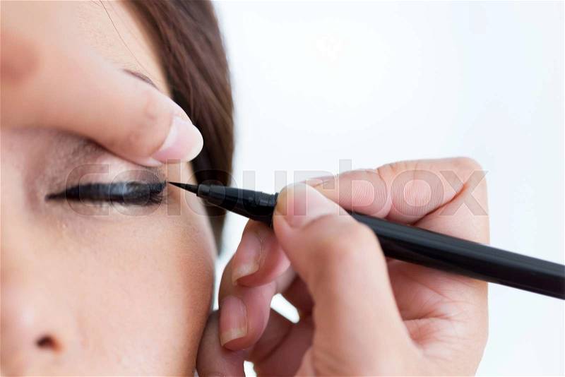 Makeup beauty with brush eye liner on pretty woman face, stock photo