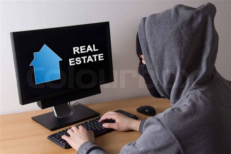 Criminal and burglary concept - thief in mask searching info about real estate in internet, stock photo