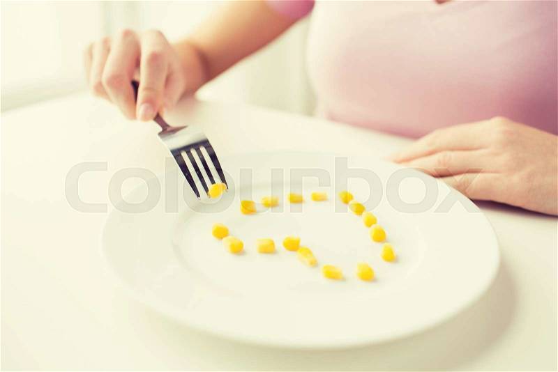 Healthy eating, dieting, vegetarian food and people concept - close up of woman with fork eating corn in shape of heart, stock photo
