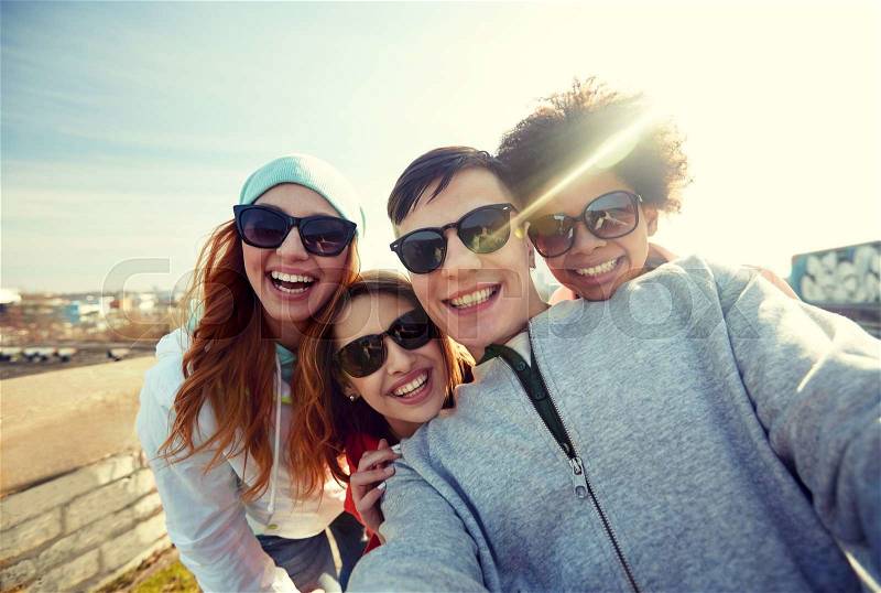Tourism, travel, people, leisure and technology concept - group of smiling teenage friends taking selfie on city street, stock photo
